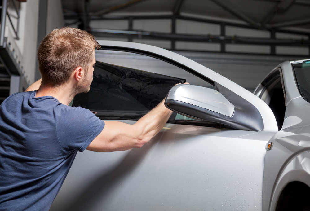 worker applying tints outside Performance Auto Group LLC